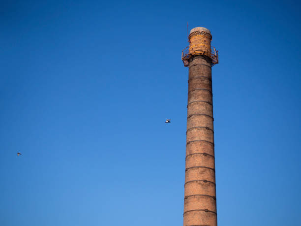 uma velha chaminé industrial contra um céu azul. - old station natural gas russia - fotografias e filmes do acervo