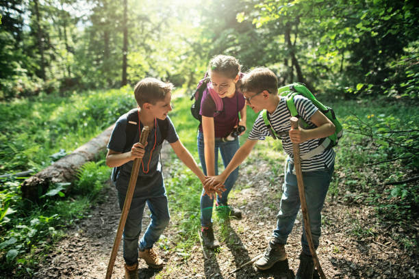 Happy kids hikers stacking hands in forest