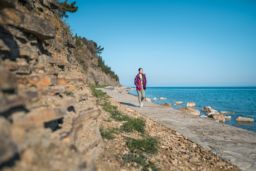 Young asian woman is walking on coastline in Slovenia. She is enjoying the sun.