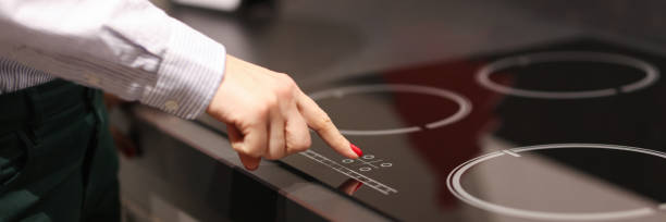 female finger presses button on touch electric stove - stove ceramic burner electricity imagens e fotografias de stock