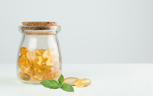 jar with omega 3 capsules and mint leaf on gray background