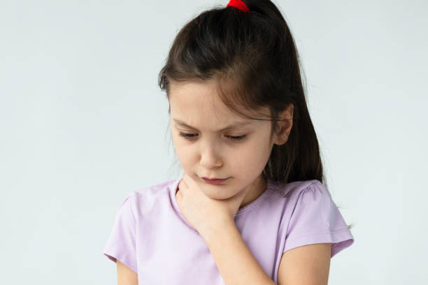 Throat Pain Little girl is holding her throat in pain in front of white background. choking stock pictures, royalty-free photos & images