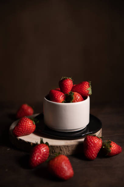 istock Ripe garden strawberries in white ceramic bowl on dark table. 1312530591