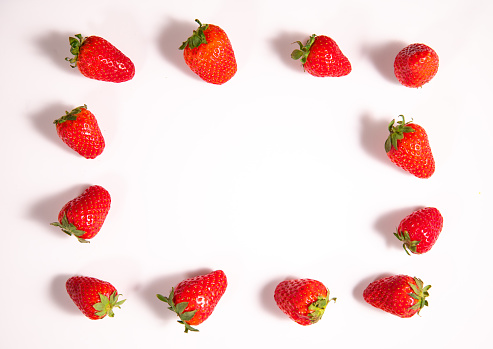 Frame made of fresh ripe strawberry berries on white background. Top view. Copy space. Flat lay. Food background.