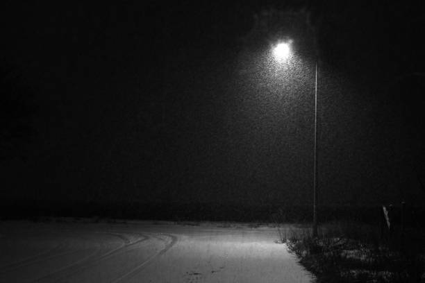 istock Snowing in empty street at night 1312533093