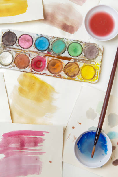 istock Watercolor paints palette, brushes and papers on table. Creative hobby or art therapy concept. 1312533412