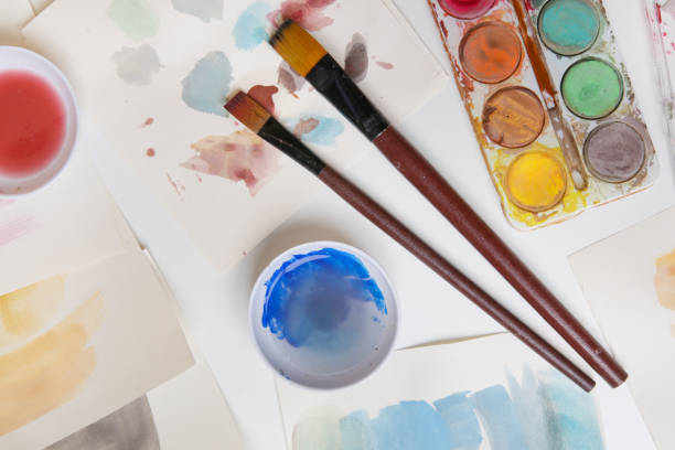 istock Watercolor paints palette, brushes and papers on table. Creative hobby or art therapy concept. 1312534206