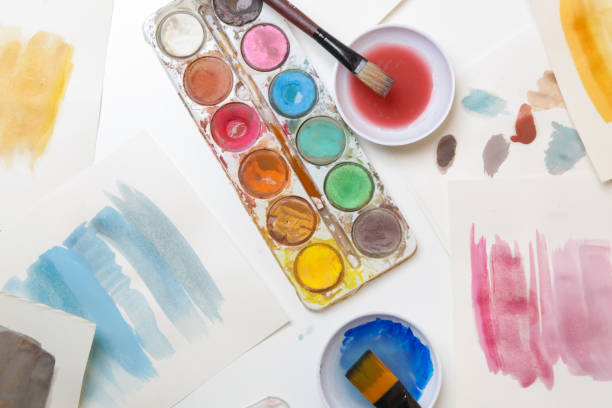 istock Watercolor paints palette, brushes and papers on table. Creative hobby or art therapy concept. 1312536612