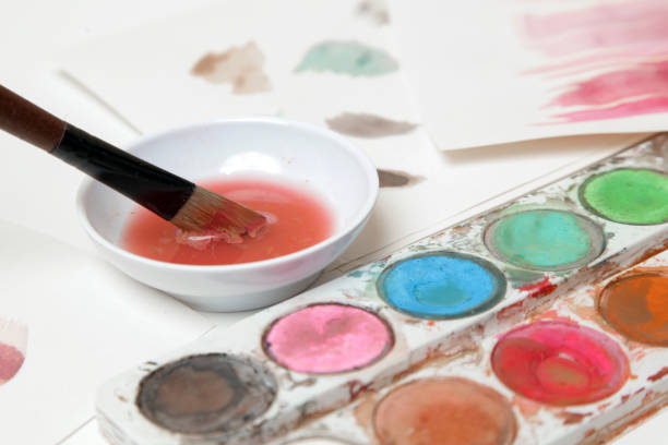 istock Watercolor paints palette, brushes and papers on table. Creative hobby or art therapy concept. 1312536614