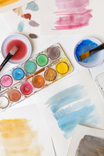 istock Watercolor paints palette, brushes and papers on table. Creative hobby or art therapy concept. 1312537267