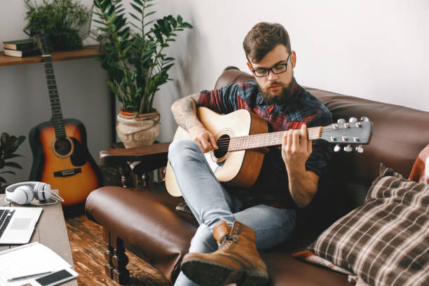 istock Young guitarist hipster at home playing guitar concentrated 1312551717