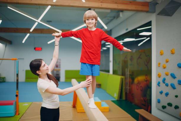 niños haciendo ejercicios de gimnasia de haz de equilibrio en el gimnasio en el jardín de infantes o la escuela primaria. concepto de deporte y fitness para niños. - barra de equilibrio fotografías e imágenes de stock