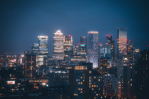 Aerial panoramic view of The City of London cityscape skyline with metropole Canary Wharf financial district modern skyscrapers at night with illuminated buildings in London, UK