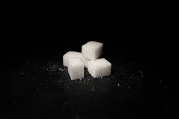 istock Sugar Cubes Are On A Black Ground And Sugar Powders Around Them 1312557922