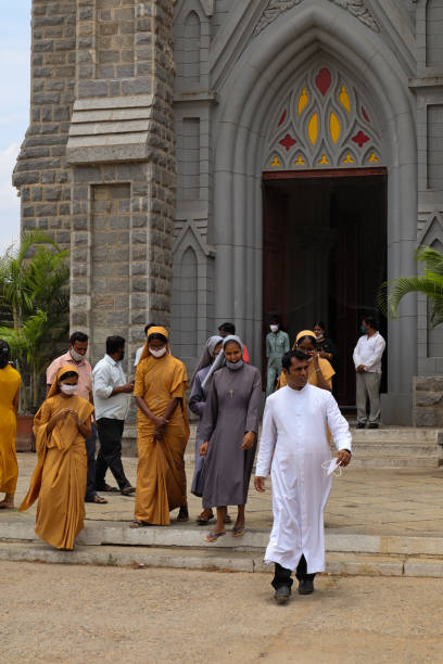 un sacerdote e poche suore che escono dalla cattedrale di san giuseppe o dalla chiesa di san filomena dopo una messa religiosa a mezzogiorno a mysuru, in india. - indian ethnicity traditional culture architecture karnataka foto e immagini stock