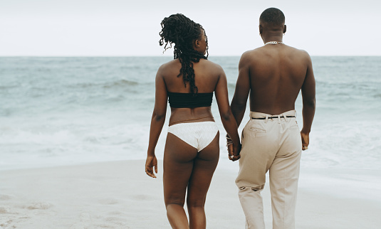 Shot of a young couple walking on the beach