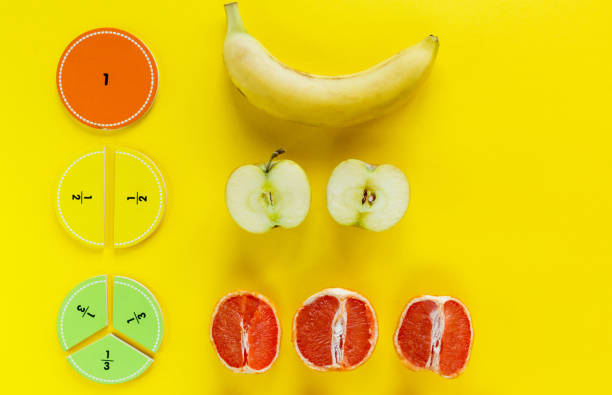 istock Colorful math fractions and apples, oranges, banana as a sample on yellow background or table. Interesting fun math for kids. Education, back to school concept. Geometry and mathematics materials. 1312563898