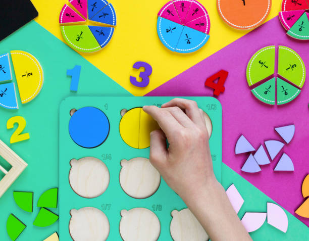 crianças movem partes de madeira de frações. brinquedos de madeira em papel colorido. frações educacionais. brinquedos para o jardim de infância, pré-escola ou creche.  jogo de matemática engraçado. educação na escola. vista superior - fraction sign - fotografias e filmes do acervo