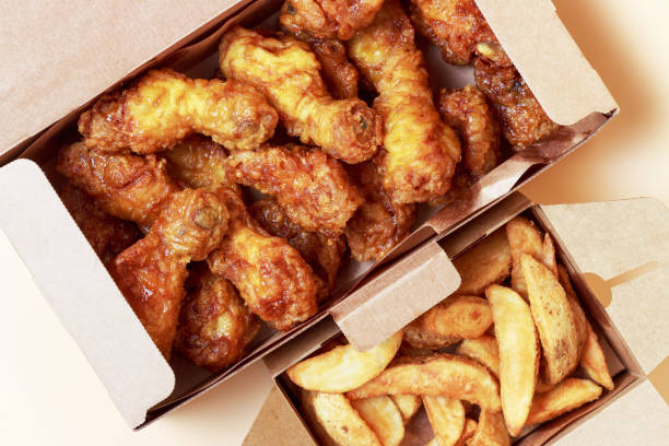 istock Two boxes with chicken legs and fried potatoes on table, top view. 1312563982