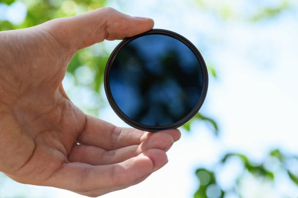 istock Hand hold  ND filter (neutral density) against blue sky. Light background. 1312570379