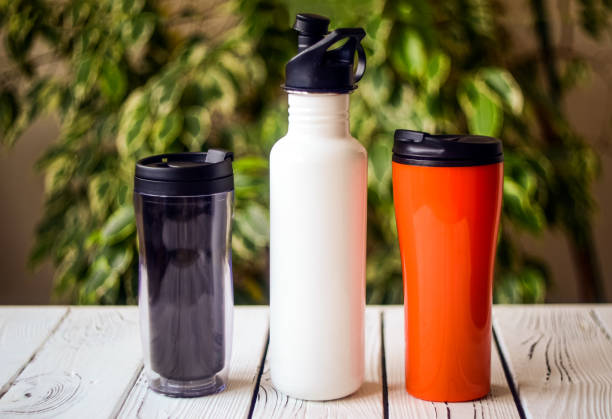 Reusable water bottles on a table Assortment of reusable plastic and stainless steel water bottles on table against blurred background. Cut down on your plastic use concept reusable stock pictures, royalty-free photos & images