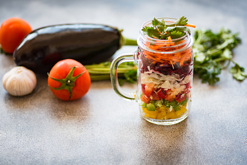 Colourful layered vegetable salad rich in phytonutrients packed in a mason jar to take to work. Horizontal front view