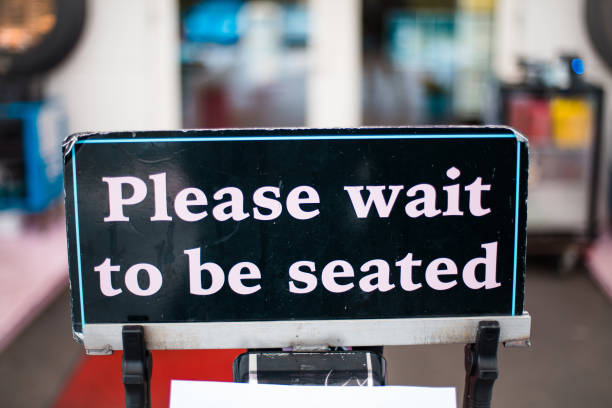 istock Sign for waiting in line to sit. Focus is on foreground. 1312572828