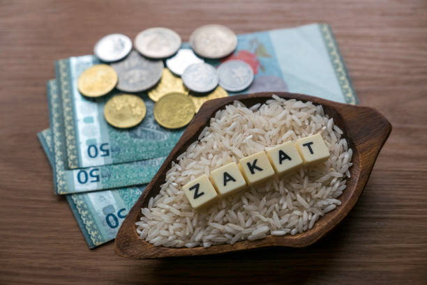 Concept of zakat in Islam religion. Selective focus of money and rice with alphabet of zakat on wooden background. Concept of zakat in Islam religion. Selective focus of money and rice with alphabet of zakat on wooden background. alms stock pictures, royalty-free photos & images