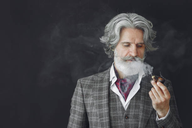 Portrait of bearded redhead English male. Senior smoking pipe in a studio.