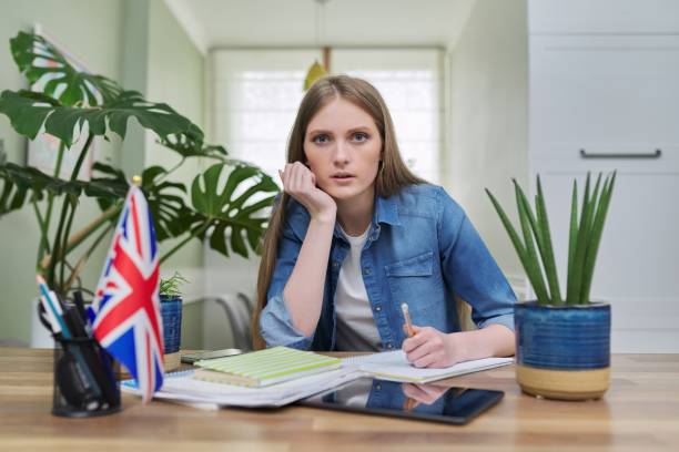 istock UK learning English online. Female student remotely looking at webcam 1312576712