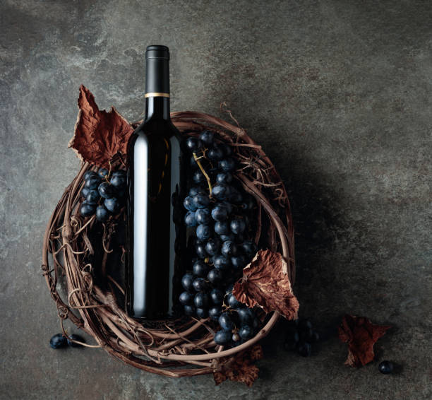 бутылка красного вина с виноградом и сушеными виноградными листьями на старом каменном фоне. - wine wine bottle cellar grape стоковые фото и изображения