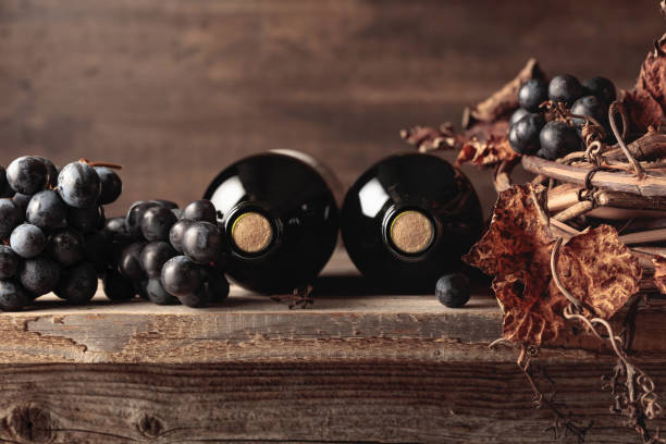 garrafas de vinho tinto com uvas e videira seca em uma velha mesa de madeira. - port wine madeira wine bottle vine - fotografias e filmes do acervo