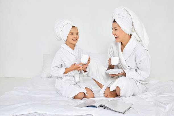 istock mother and daughter in white bathrobes drinking tea 1312582982