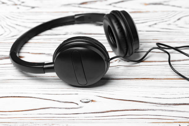 istock Black headphones with wire on wooden background 1312583836
