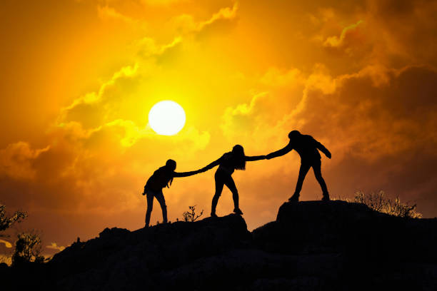 istock Teamwork friendship walking in the mountains, helping each other trust, silhouette helping, sunrise. Mountain climbing team help each other on top of beautiful sunrise landscape. milky way view 1312583860