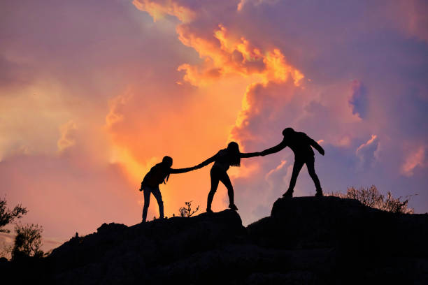istock Teamwork friendship walking in the mountains, helping each other trust, silhouette helping, sunrise. Mountain climbing team help each other on top of beautiful sunrise landscape. milky way view 1312583861