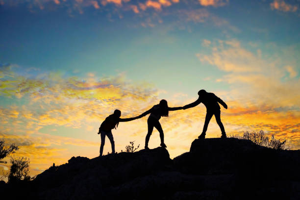 istock Teamwork friendship walking in the mountains, helping each other trust, silhouette helping, sunrise. Mountain climbing team help each other on top of beautiful sunrise landscape. milky way view 1312583864