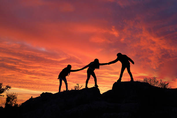 istock Teamwork friendship walking in the mountains, helping each other trust, silhouette helping, sunrise. Mountain climbing team help each other on top of beautiful sunrise landscape. milky way view 1312583870