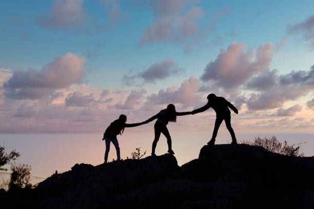 istock Teamwork friendship walking in the mountains, helping each other trust, silhouette helping, sunrise. Mountain climbing team help each other on top of beautiful sunrise landscape. milky way view 1312583871