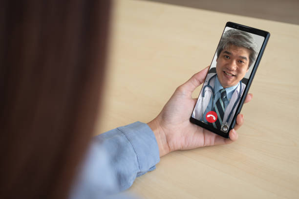 istock Asian doctor or therapist help relieve stress and provide knowledge and understanding about office syndrome to patients video conference call online live talk remotely at home by smartphone 1312584120