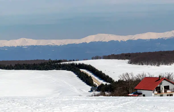 Ski slope near a guesthouse with a view of other distant mountains surrounded by forests