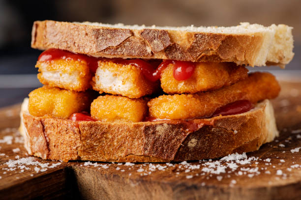 Fish Finger Sandwich with Tomato Ketchup A staple of the english diet a “Fish Finger Sandwich”. Fried fish fingers between two slices of buttered white bread, oozing with tomato ketchup! A snack, a meal, a hangover cure, you decide! Delicious. Colour, horizontal format with some copy space. fish stick stock pictures, royalty-free photos & images