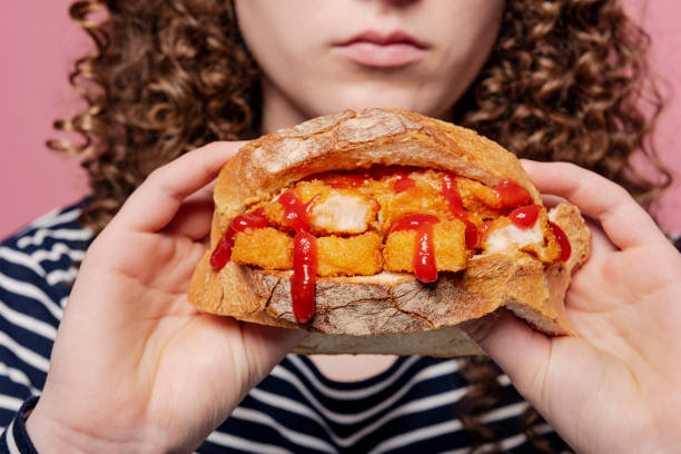 Fish Finger Sandwich With Ketchup Young woman holding a staple of the english diet a “Fish Finger Sandwich”. Deep fried fish fingers between two slices of buttered white bread, oozing with tomato ketchup! A snack, a meal, a hangover cure, you decide! Delicious. Colour, horizontal with some copy space. fish stick stock pictures, royalty-free photos & images