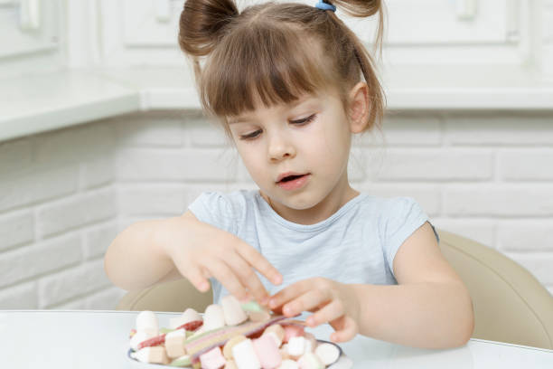 istock child girl sitting at the kitchen table with sweets 1312586545