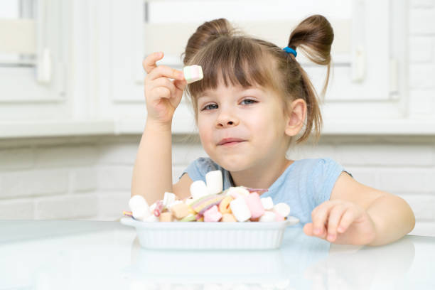 istock girl sitting at the kitchen table and eating sweets 1312586552