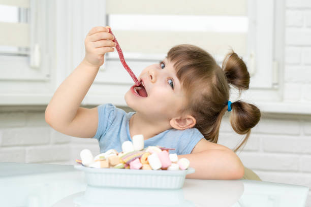 istock girl sitting at the kitchen table and eating sweets 1312586554