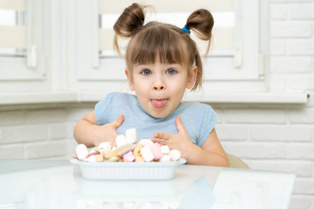 istock kid girl sitting at the kitchen table with sweets 1312586557