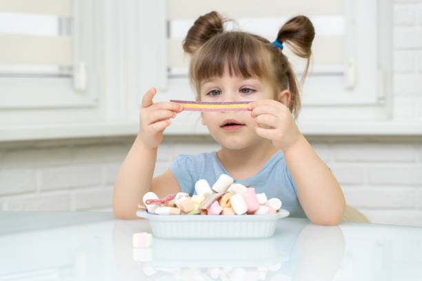 istock girl sitting at the kitchen table and eating sweets 1312586560