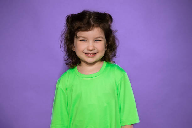 joven hermosa chica sonriente 4-5 años en fondo púrpura - child 4 5 years laughing little girls fotografías e imágenes de stock