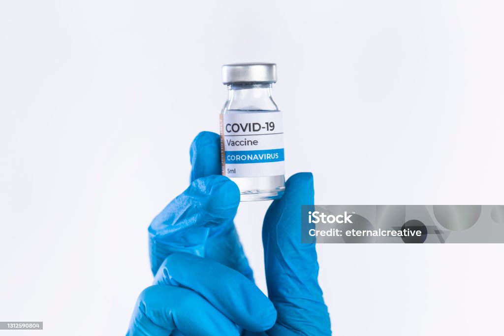 Hand in protective glove holds Covid-19 Vaccine glass vial Doctor hand in protective glove holds Coronavirus Covid-19 Vaccine glass bottle. Coronavirus 2019-nCoV concept COVID-19 Vaccine Stock Photo